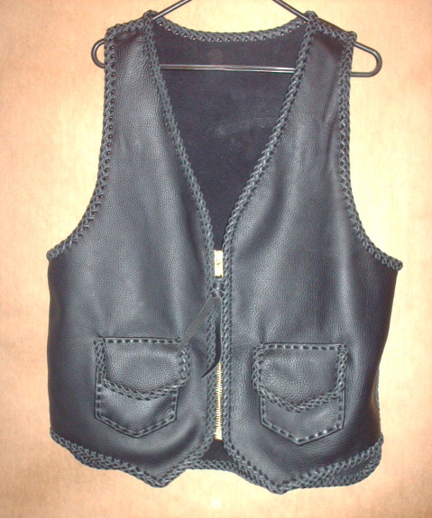  The black motorcycle vest has a large brass (YKK #10) zipper and two patch pockts with flaps. It also has a 3" back/bottom draft flap extension. 