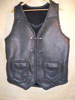  This braided motorcycle vest has slanted front yokes, a pointed back yoke, patch hip pockets with flaps, two sets of 'trick braid' leather snap closures, and a curved 3" back/bottom draft flap. This vest also has four more pockets that you can't see in this picture. Clicking on the link will bring you to (7 more) pictures of it's different features. 