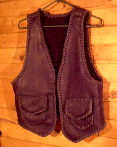  This black motorcycle leather vest was custom made in the USA with moccasin cowhide. It has two patch hip pockets with flaps and two more similar pockets on the inside using the same braiding to attach them. These inside pockets do not have flaps. 