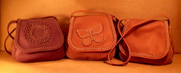  This picture shows the usual three ways that I build these braided leather handbags. One has a braided circle on the flap, another has a butterfly braided on the flap, and the third one has a plain flap. All of these bags' seams, flap edges, and appliques are braided using 1/4" wide laces of the same leather the bag is made. 