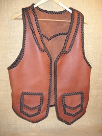  This western style two tone leather vest was built with moccasin cowhide. It has front lapels, a back pointed yoke, and two patch hip pockets with flaps. 