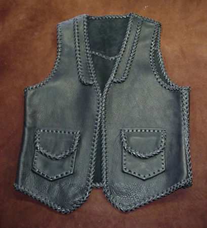  This leather vest has all of it's seams and edges braided. It also has braided lapels on the front, a pointed yoke on the back, and two patch hip pockets with flaps. It also has matching hip pockets on the inside of the front (without flaps). 