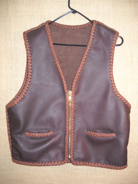  This two tone Brown leather vest is completely hand braided using moccasin cowhise tanned in the USA. It featurs a large brass (YKK #10) zipper and two slit hip pockets. At the buyers request, this was is squared off completely across the bottom (front and back panels). 