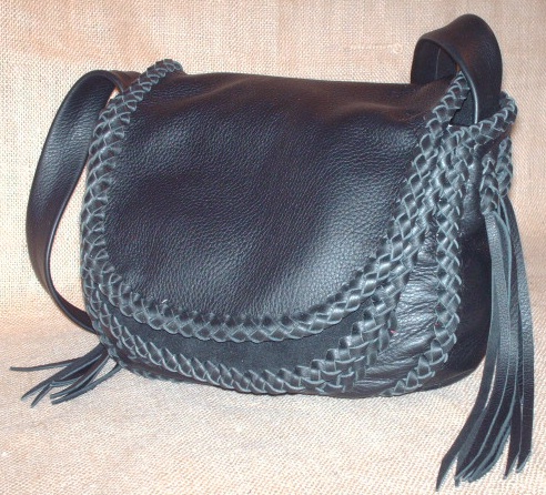  This custom and handmade leather purse is constructed with 4 oz. moccasin cowhide. All of the pieces of the purse are braided together with 1/4" wide laces cut from the same soft strong leather the bag is made with - all of the seams are joined with an applique braid, it's double flaps are braided all around their edges, the front pocket is attached with braiding, the strap has an applique braid down the center/length of it ...and the strap is attached with a braid that long tassels hang from. 