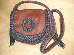  This handmade custom leather purse was made with Mahogany pieces braided together with dark Brown laces. Like a lot of the purses and handbags that I make, it has no hardware, lining, or thread. Completely braided with 1/4" wide lacing are the seams, the edges of the flaps, and down the center/length of the strap. There are long tassels hanging from the strap attachments. It has a circle applique braided on the flap. This purse also has two pockets - one under the flap/s and another full width pocket on the inside/back. 