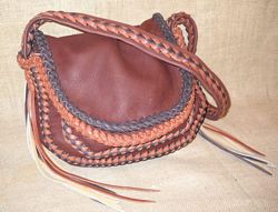  This leather purse is made with four colors. The pieces of the bag are all Mahogany. The color of the leather around its top flap and one of the colors used on the two-tone seams is dark Brown. The color Rust is used around the under flap and is the other color used on the seams. This one has a braided strap with the same two-tone braid down the length of it. The lightest color, Walnut, is used for some of the side tassels.
