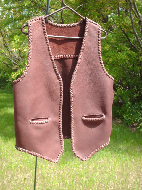  This brown moccasin cowhide leather vest has no front lapels or yokes. It does have a straight back yoke and slit hip pockets (without flaps). 