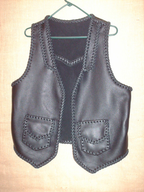  This custom black leather vest was made with moccasin cowhide leather. It's features include lapels on the front, a back pointed yoke, and two patch hip pockets with flaps. 