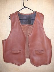  This two tone moccasin cowhide leather vest has braided leather seams, edges, back yoke, and pocket tops. The laces for it are cut from the same leather that the parts of the vest are cut from. The back yoke, of a darker color, is suede side out. 