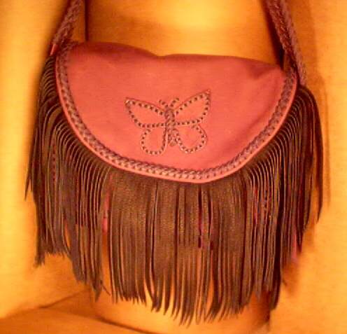  This large leather purse with fringe was completely built using 1/4" wide laces to braid all of the seams, edges, strap, etc. The flap and sides of it have fringe hanging from them. The long strap has three lengths of braids running the length of it. It has a full width pocket on the back side of it. The large brass zipper under the flap was hand sewn using 5 ply nylon thread. The zipper's slider/tab has a long leather strap hanging from it. 