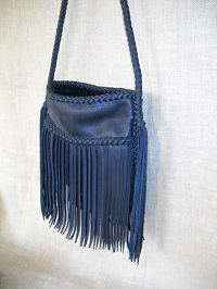 This leather purse with fringe is about 8" wide and 8" high and has an open top. The 8 strand round braided strap has long tassels hanging from each end. 