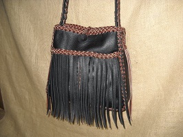  This leather purse with fringe has a flat strap that is braided down the center/length of it. The open top has a braid around that top edge. 