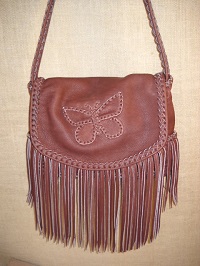  A large Mahogany colored leather purse with a butterfly applique on the flap. It has fringe hanging from the flap and side pockets.  It's entirely constructed using 1/4" wide laces cut from the same 4 oz. moccasin cowhide that the bag is made with. The purse is made of/with 100% leather - it has no lining, hardware, nor thread. 