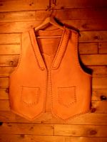  This moccasin cowhide leather vest was custom built for the buyer. It has lapels on the front, a pointed yoke on the back, and two patch hip pockets that also have matching pockets on the inside. 