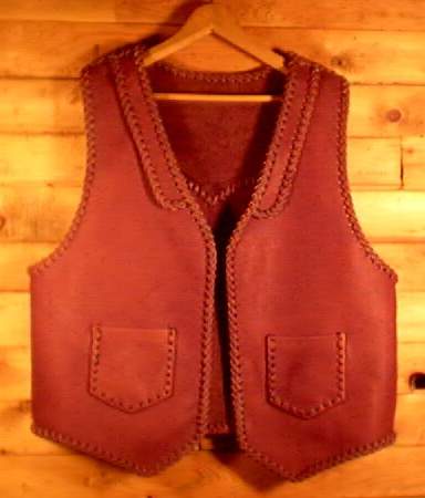  This custom built vest was made in the USA using moccasin cowhide leather tanned in the USA. It has lapels in front and a pointed yoke on the back. It's patch hip pockets are attached with a simple braid and these pockets also have matched pockets on the inside (four pockets in all). 