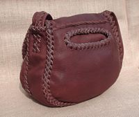  This view of the back of this purse shows the large back pocket's oval opening. You can see how the wide strap is attached. Sometimes tassels hang from the strap attachment. 