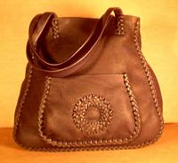  This large Black tote has a more elaborate braid on the bags seams. It also has a circle applique on the large front pocket and another full width back/inside pocket. 