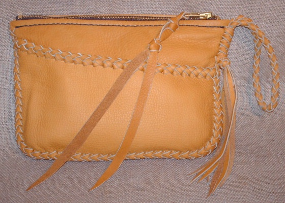  This leather clutch purse is completely made with a braided construction ...such as its main seam, the top of the pocket, and the wrist strap with tassels hanging from it. It has a large brass zipper closure with a leather strap fastened to the tab/slide. It's about 9" wide by 6" high. 