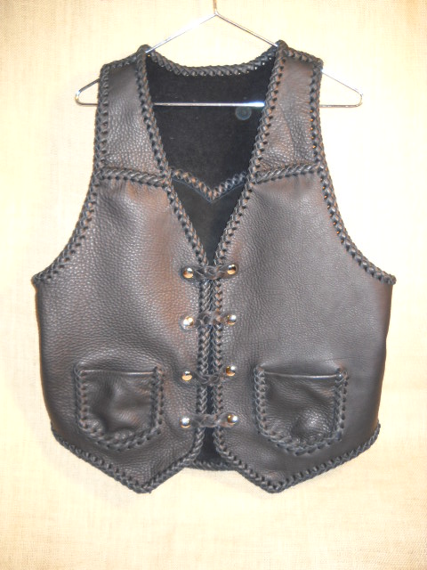  This black moccasin cowhide leather vest has slanted front yokes, a pointed back yoke, two patch hip pockets (without flaps), and four sets of 'trick braided' leather snaps for closures. It also has the draft flap that so many of my customers have taken a liking to. This draft flap is a 3" extension of the back that can better be seen on the page that this picture is linked to. 