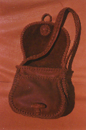  In this picture the purse is lying on it's back with the flap open, you can see the the two compartments that are under the flap. You can see the braided seams, flap edges, strap, and the roll button closure that it has. 