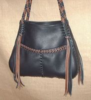  This Black tote with two tone (Black and Mahogany) braiding has long should straps that have long fringe hanging from the ends of them. The straps are also fastened in a different location than the other straps are. It does have the two front pockets and the inside back pocket that the others have. 