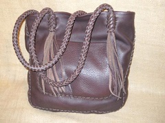 This tote is very much a one of a kind. It was built with full grain, dark Brown, moccasin cowhide leather. It has an outside pocket on the front and a full width pocket on the inside/back. The straps are eight strand round braided with eight strands of long tassels hanging from each end. 