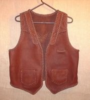  This brown moccasin cowhide leather vest has both lapels and slanted yokes on the front of it - that's what the buyer wanted. It also has a pointed back yoke, a single slit breast pocket (credit dard size), and two patch hip pockets (with matching inside pockets). The picture is linked to a page of more views of the vest and its features. 