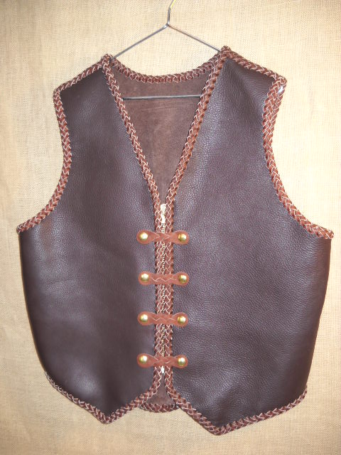  This two tone leather vest was built with moccasin cowhide. It has 4 sets of 'trick braided' snaps and a zipper for closure. It has no pockets. It does have the back/bottom draft flap that many folks like.  