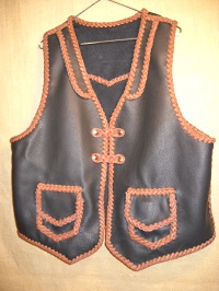  This two tone western style vest is built with moccasin cowhide leather including for the braided lacing. It has front lapels, a back pointed yoke, patch hip pockets with flaps and two sets of snap closures braided with what is called a 'trick braid'. 