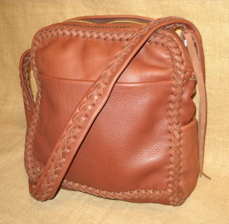 These messenger leather purses are built using a braided construction method with strong, supple, long lasting 4 oz. moccasin cowhide leather. Handmade, no electricity is used to build them. They all have large brass zippers (YKK #10) that are attached with hand sewn 5 ply nylon thread. This particular bag is made with Rust colored leather. The dimensions of it are about 10" wide by 11" high by 4". It has a full width pocket on the front and another full width pocket on the inside/back. It also has pockets on each side whose 4" width make them quite usable. 