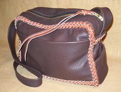  This two-tone one is also 12" wide by 10" high by 4" with about a 16" long zipper. It also has four pockets ...one of them being on the inside/back. It's long wide/flat strap is not braided. 