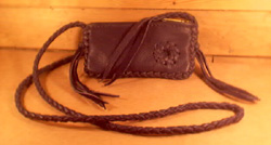  This small Black bag is about 7" long by 4" high and has a zipper across the top of it. It has a 4 strand round braided strap that has long tassels hanging from the ends of it. It has a small circle applique braided to the side of it. 