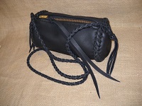  This Black barrel bag is about 9" long with a 5" diameter and has zipper across the top of it. It has a 4 strand round braided shoulder strap with long tassels hanging from the ends of it. It also has a very long strap of leather tied to the zipper tab/slide. 
