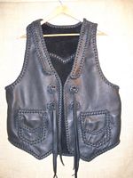 This custom, handmade moccasin cowhide leather vest was made in the USA using leather that was tanned in the USA. It features front lapels, a pointed back yoke, two patch hip pockets with flaps, and some straps that hang from some braided leather conchoes that I fashioned. Clicking on it will bring you to a page of more closer pictures of these features. 